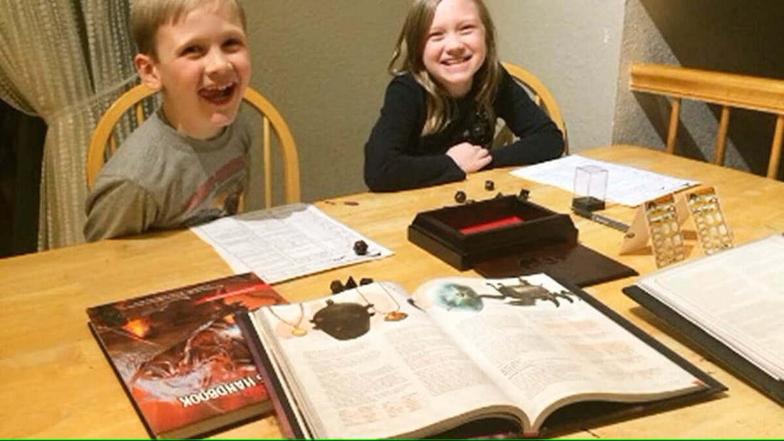 Two children smiling at a table set up for TTRPGs, showcasing the role of social interactions in gaming.